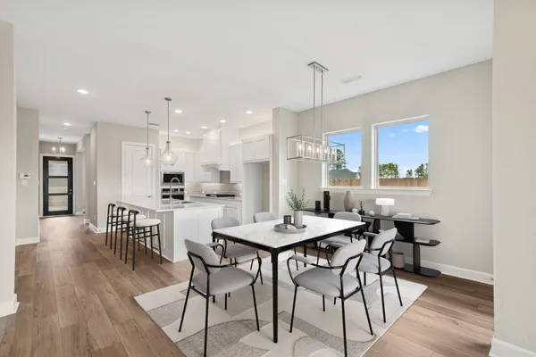 a kitchen with a dining table chairs wooden floor and appliances