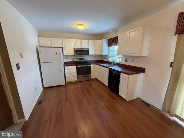a kitchen with a sink a refrigerator a stove and wooden floor