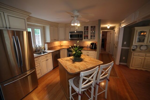99 Spallus Road Stoughton, MA 02072 - Photo 5 of 14 a kitchen with stainless steel appliances granite countertop a refrigerator a stove a sink dishwasher a dining table and chairs with wooden floor