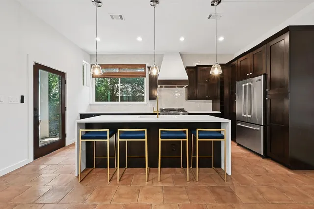 a kitchen with kitchen island granite countertop a table chairs refrigerator and microwave