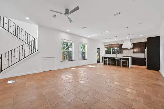 a view of an empty room with a window and kitchen view