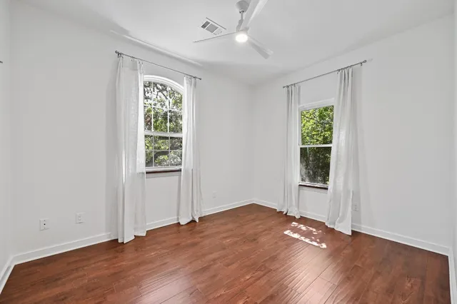an empty room with wooden floor cabinet and windows
