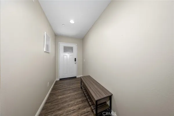 a view of a hallway with wooden floor and a bathroom