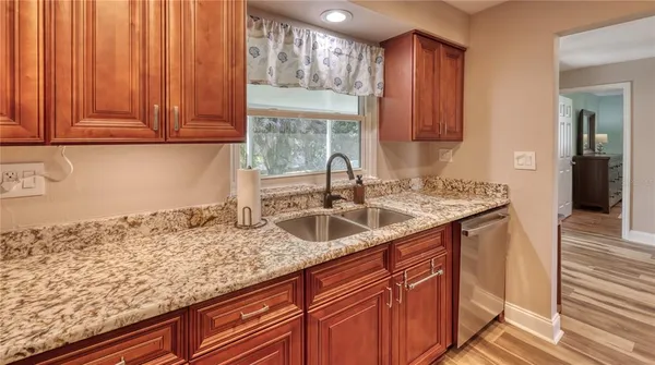 a kitchen with granite countertop wooden cabinets a sink and dishwasher