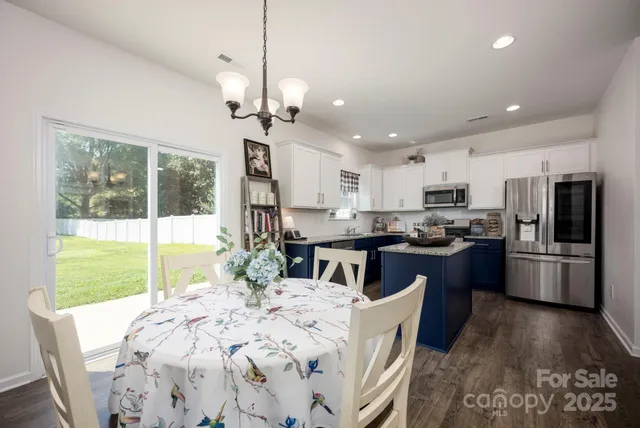 a kitchen with stainless steel appliances kitchen island granite countertop a refrigerator a stove top oven a sink a dining table and chairs