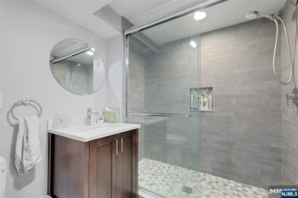 514 Rutland Avenue Teaneck, NJ 07666 - Photo 29 of 40 a bathroom with a sink a mirror and a shower