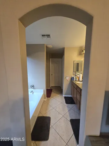 a spacious bathroom with a tub sink and mirror