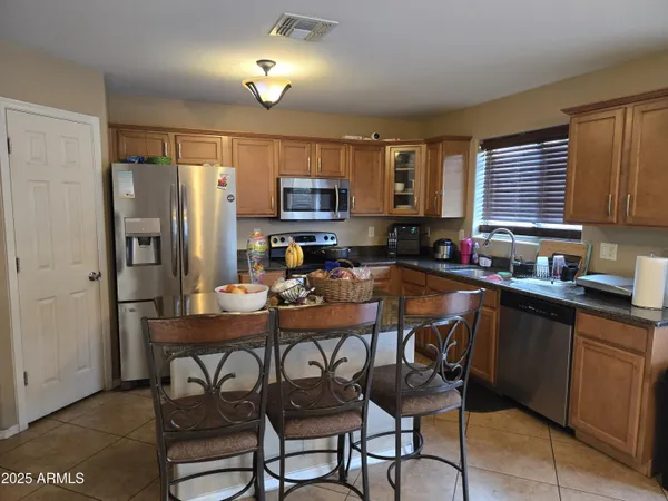 a kitchen with sink a refrigerator and chairs