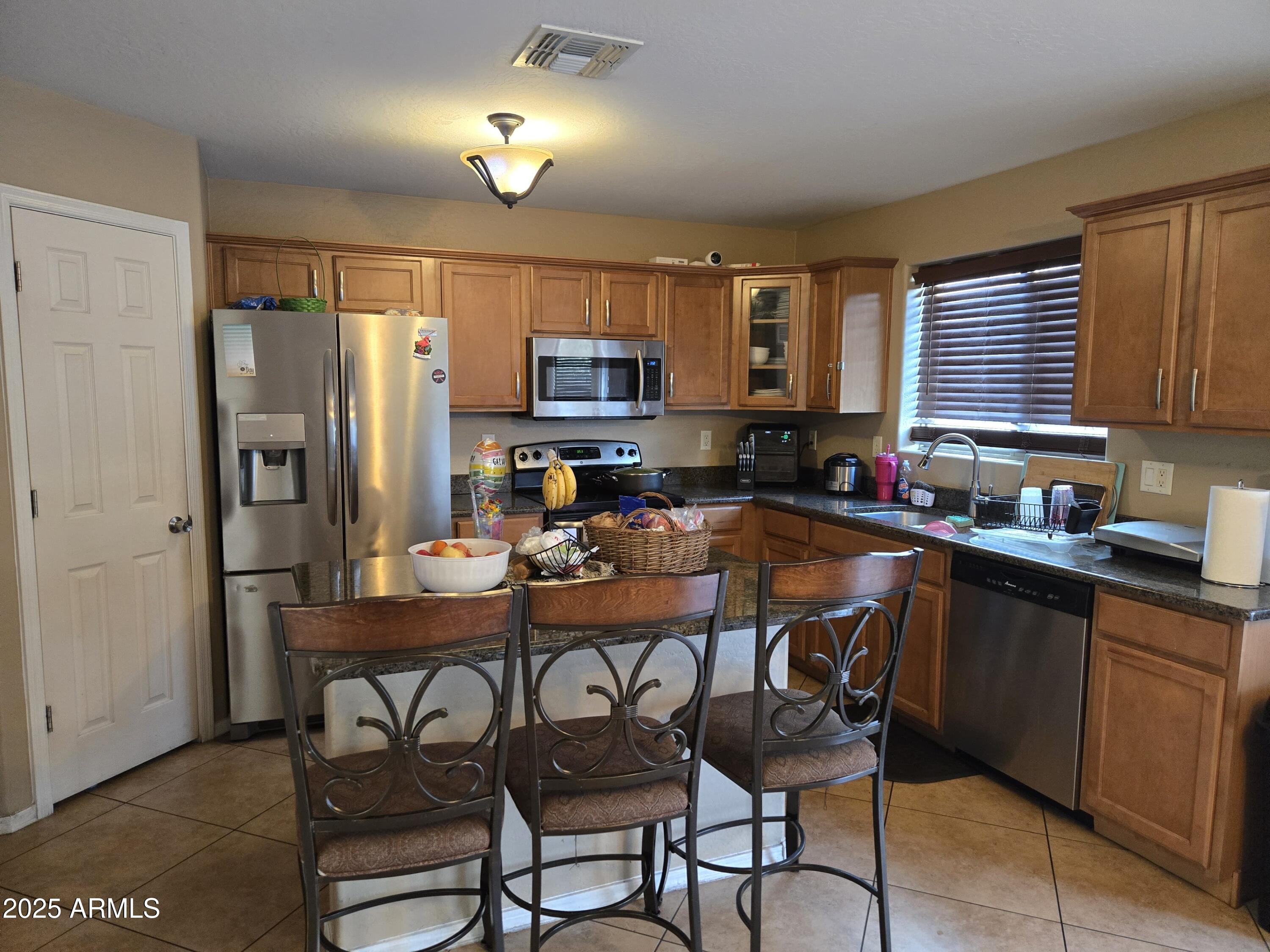 8814 West Magnolia Street Tolleson, AZ 85353 - Photo 4 of 19 a kitchen with sink a refrigerator and chairs