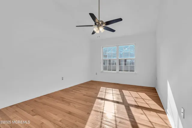 an empty room with windows and fan