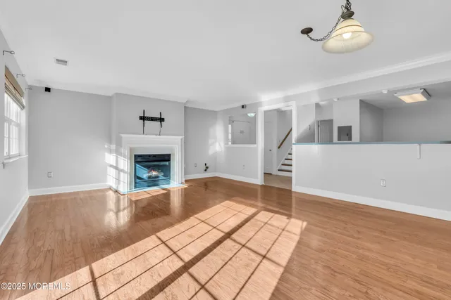 a view of an empty room with wooden floor and a fireplace