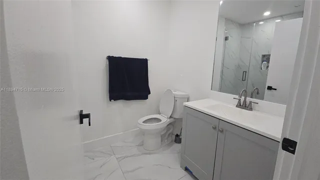 a bathroom with a granite countertop toilet sink and mirror