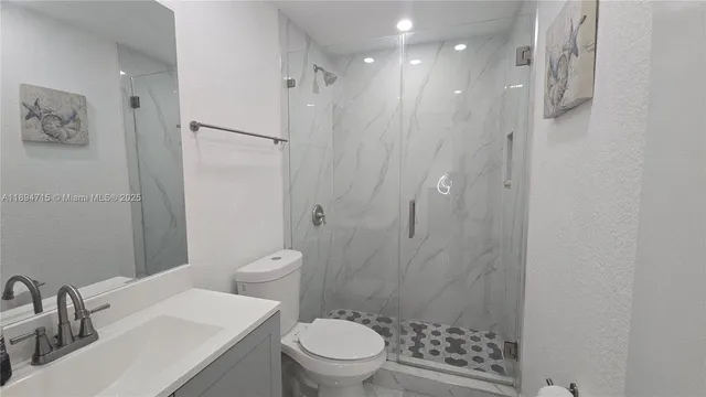 a bathroom with a granite countertop sink a toilet and shower