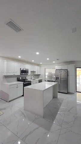 a large kitchen with kitchen island a sink counter top stainless steel appliances and cabinets