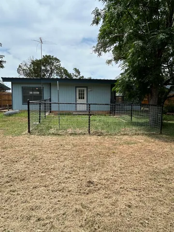 a backyard of a house with plants and large tree