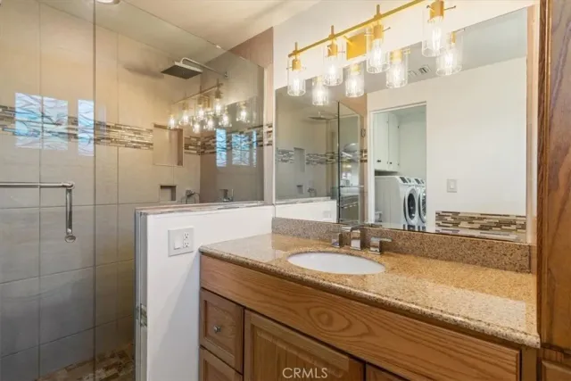 a bathroom with a granite countertop sink a mirror and shower