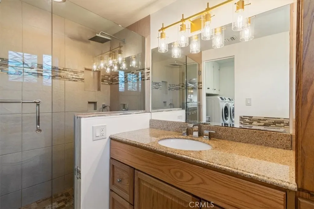 15657 Devonshire Street Granada Hills, CA 91344 - Photo 12 of 39 a bathroom with a granite countertop sink a mirror and shower