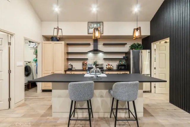 a kitchen with stainless steel appliances kitchen island granite countertop a table chairs sink and cabinets
