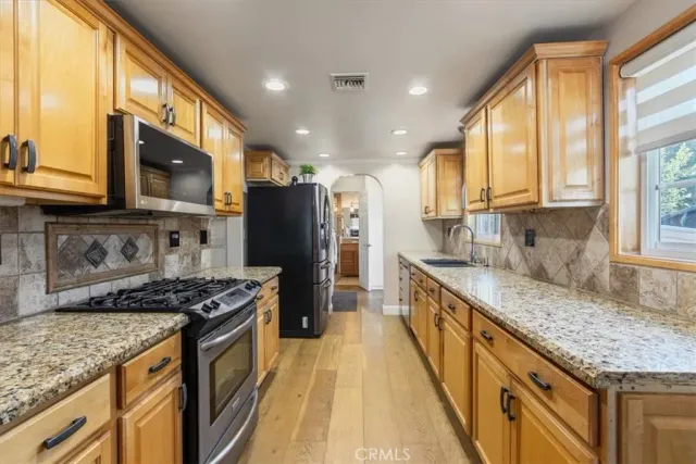 a kitchen with stainless steel appliances granite countertop a stove a sink dishwasher a refrigerator and a microwave