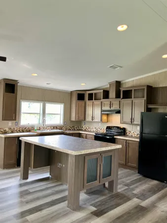 a kitchen with stainless steel appliances granite countertop a stove a sink dishwasher a refrigerator and white cabinets with wooden floor