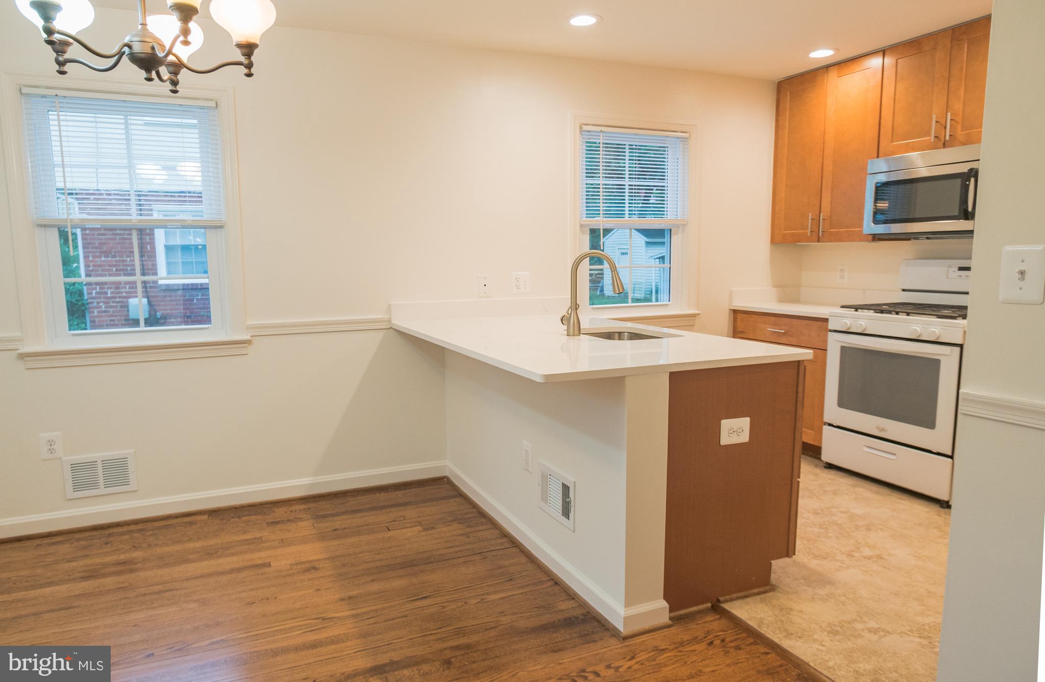 1613 Neely Road Silver Spring, MD 20903 - Photo 18 of 53 a kitchen with stainless steel appliances granite countertop a sink a stove a refrigerator a microwave oven with wooden floor and cabinets