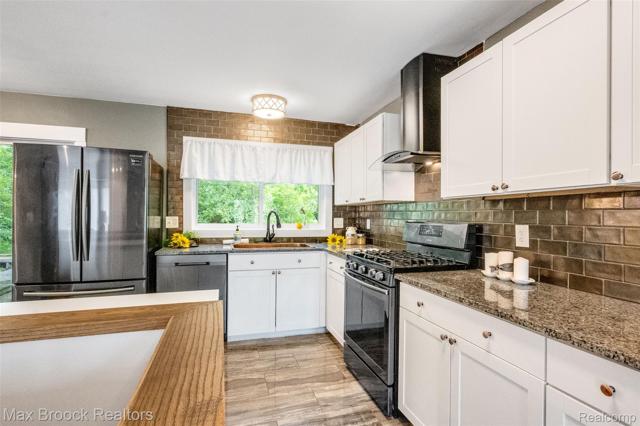 2905 Lahser Road Bloomfield Hills, MI 48304 - Photo 8 of 28 Kitchen featuring white cabinetry, granite countertops, a dark subway tile backsplash, stainless steel appliances, and wood-finish flooring