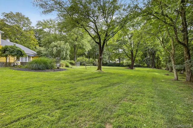 a view of grassy field with benches and trees all around