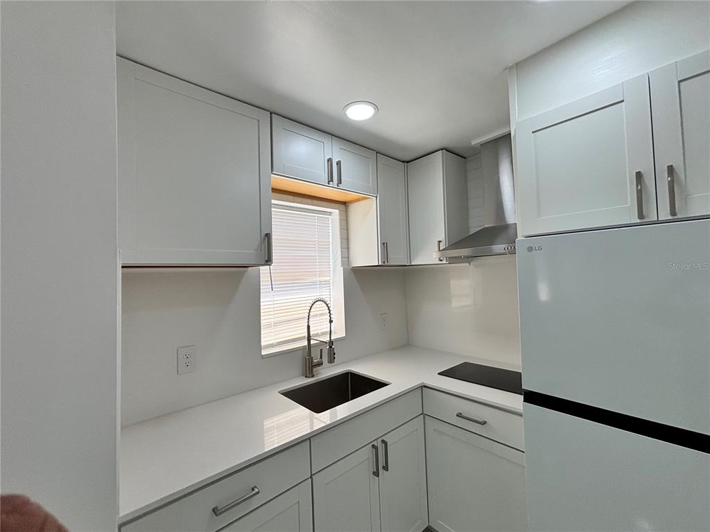 124 Coronado Road, Unit B DeBary, FL 32713 - Photo 2 of 18 a kitchen with a sink a refrigerator and cabinets