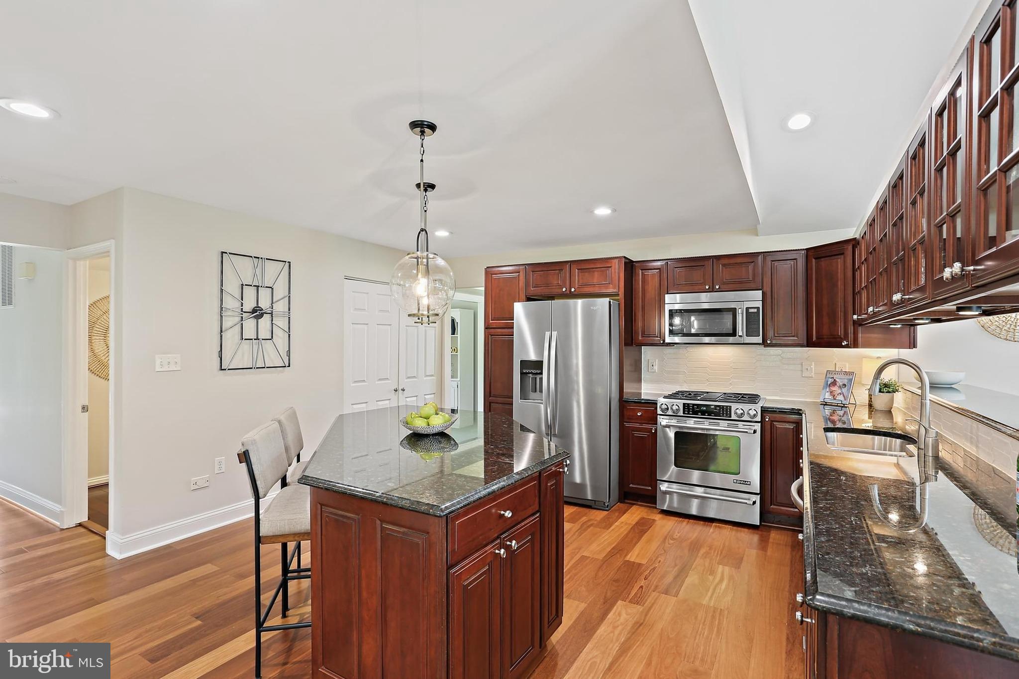 2111 Stonewall Road Baltimore, MD 21228 - Photo 10 of 58 a kitchen with stainless steel appliances granite countertop a refrigerator a stove top oven and a dining table with wooden floor