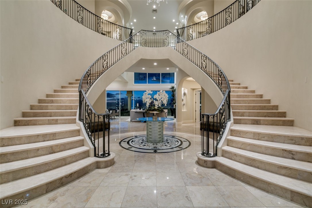 Foyer with stairway, marble tiled flooring, a high ceiling, arched walkways, and recessed lighting