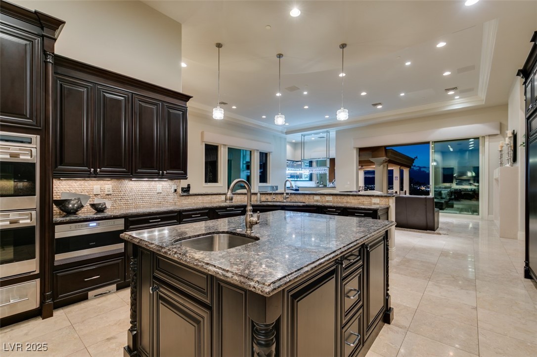 4 Awbrey Court Henderson, NV 89052 - Photo 19 of 72 Kitchen featuring dark stone countertops, backsplash, recessed lighting, a center island with sink, and pendant lighting