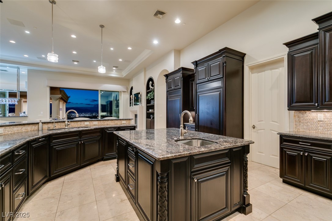 4 Awbrey Court Henderson, NV 89052 - Photo 20 of 72 Kitchen with dark stone counters, a kitchen island with sink, decorative light fixtures, backsplash, and recessed lighting