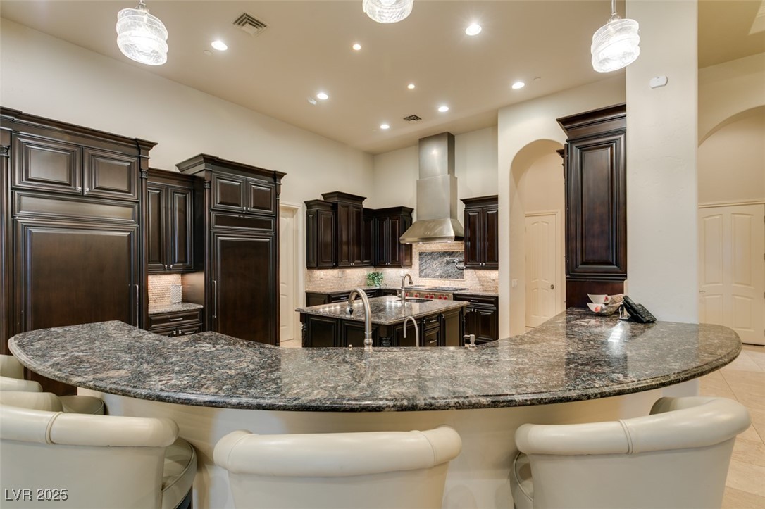 4 Awbrey Court Henderson, NV 89052 - Photo 21 of 72 Kitchen featuring decorative light fixtures, backsplash, dark stone countertops, recessed lighting, and a breakfast bar area