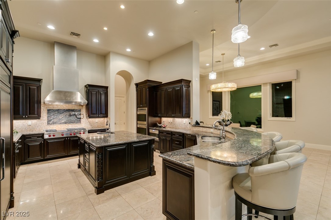 4 Awbrey Court Henderson, NV 89052 - Photo 23 of 72 Kitchen with an island with sink, dark stone counters, pendant lighting, a peninsula, and recessed lighting