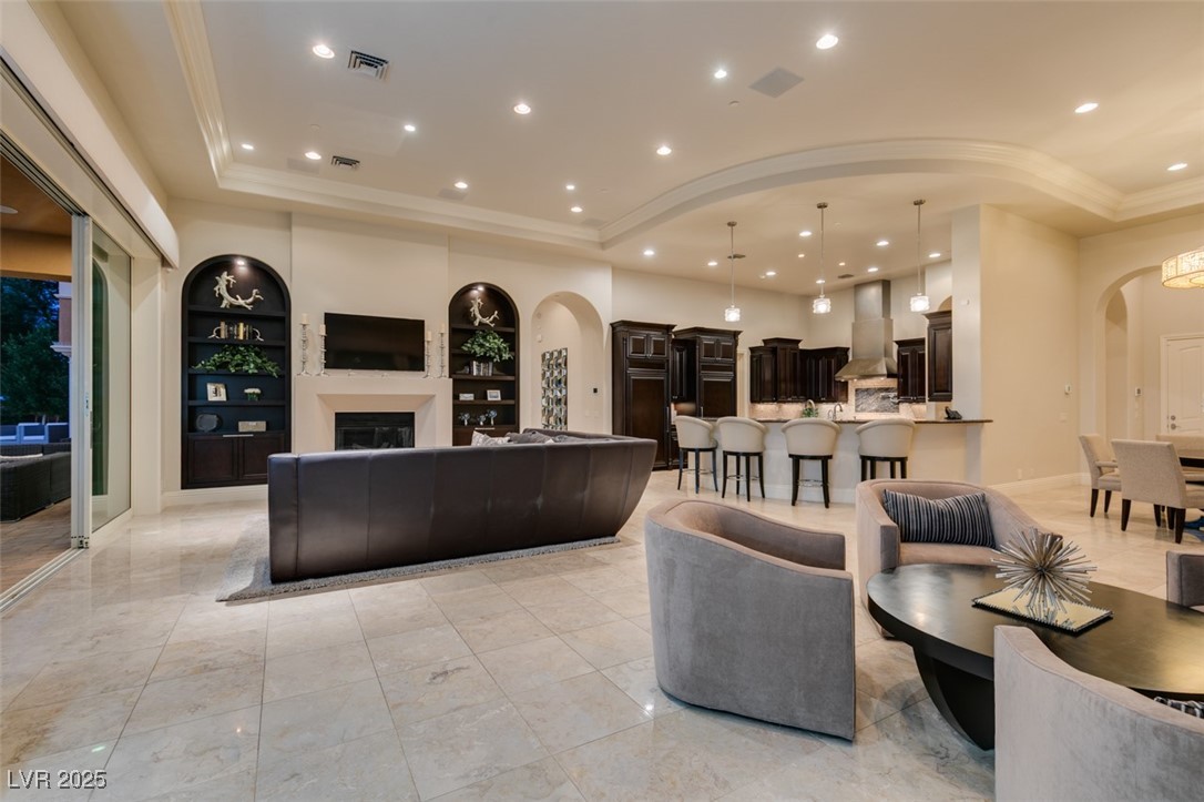 4 Awbrey Court Henderson, NV 89052 - Photo 27 of 72 Living area with arched walkways, recessed lighting, a tray ceiling, built in features, and a fireplace