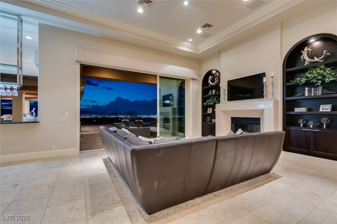 4 Awbrey Court Henderson, NV 89052 - Photo 29 of 72 Living area with a fireplace, built in shelves, ornamental molding, light tile patterned flooring, and a tray ceiling