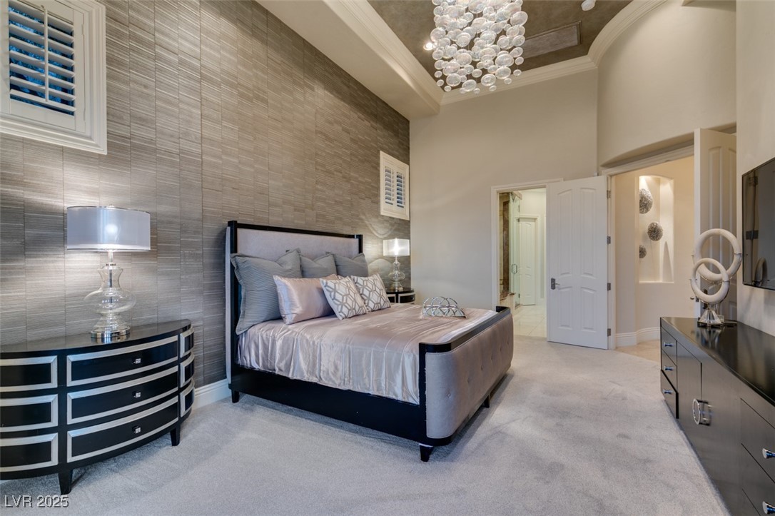 4 Awbrey Court Henderson, NV 89052 - Photo 39 of 72 Bedroom with a towering ceiling, light colored carpet, crown molding, and a chandelier