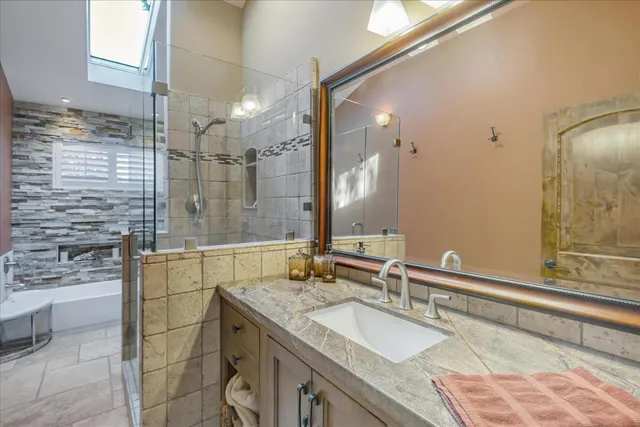 a bathroom with a granite countertop sink a mirror and shower