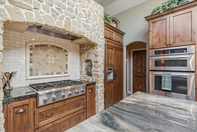 a kitchen with granite countertop a stove and a wooden cabinets