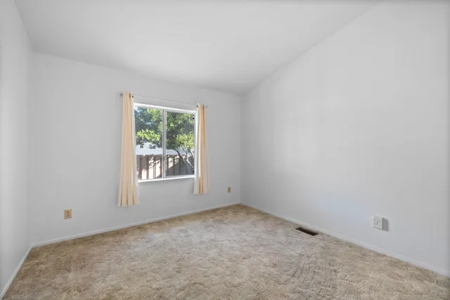 an empty room with chandelier fan and windows