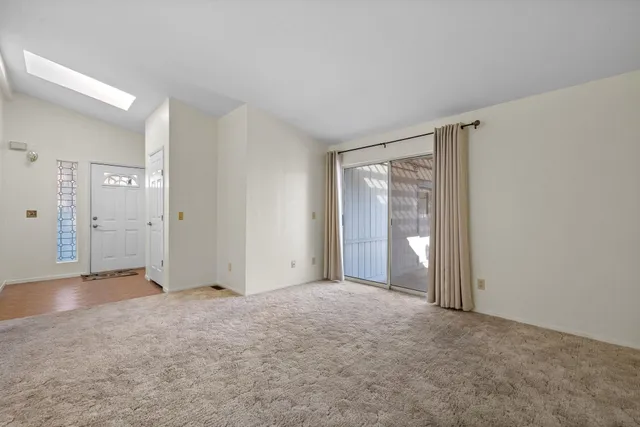 an empty room that has a window and kitchen view