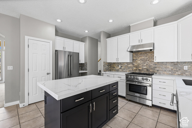14038 New Saddle Road Draper, UT 84020 - Photo 7 of 46 Kitchen featuring a dark-toned island with a light-toned countertop, white cabinetry, stainless steel appliances, and a tiled backsplash