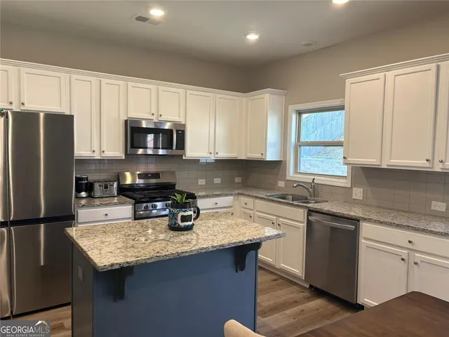 a kitchen with a sink a center island stainless steel appliances and cabinets
