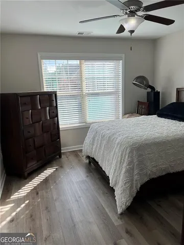 a view of a room with wooden floor a ceiling fan and a window