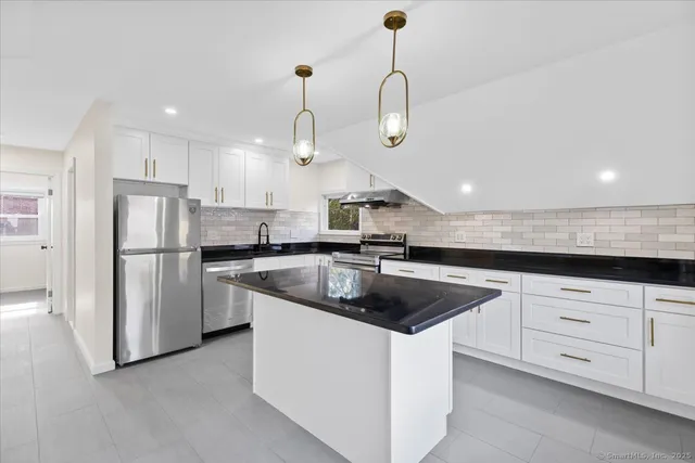 a kitchen with stainless steel appliances granite countertop a sink a stove and a refrigerator
