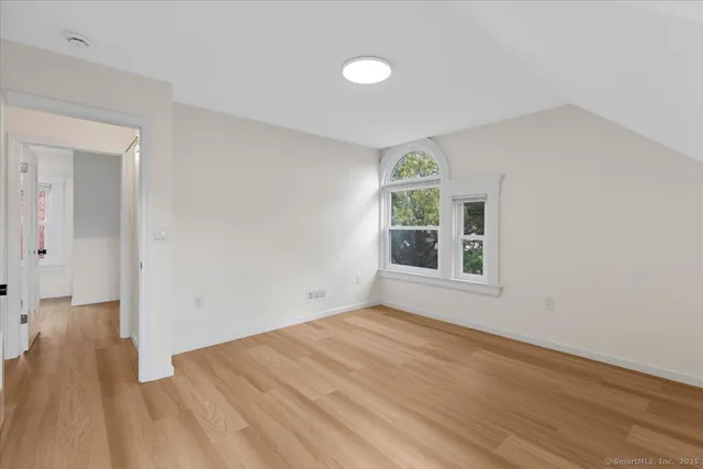 a view of an empty room with wooden floor and a window