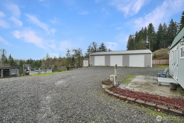 a view of a white house with a yard and large trees