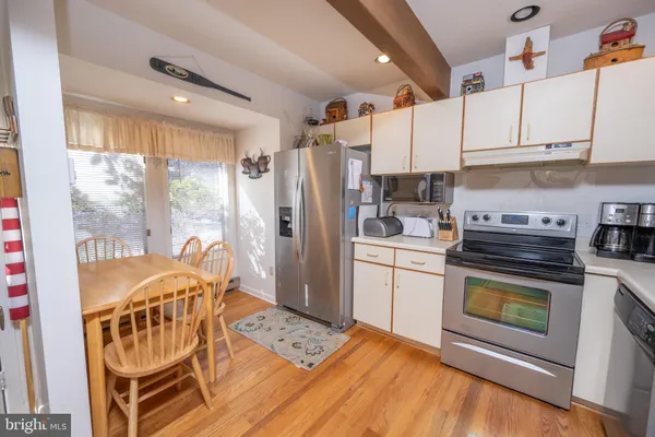 a kitchen with stainless steel appliances granite countertop a refrigerator a stove and white cabinets with wooden floors