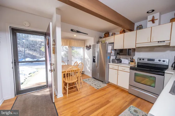 a kitchen with stainless steel appliances granite countertop a refrigerator a stove top oven and white cabinets with wooden floors