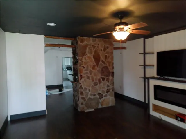 a view of a livingroom with wooden floor a ceiling fan and a window